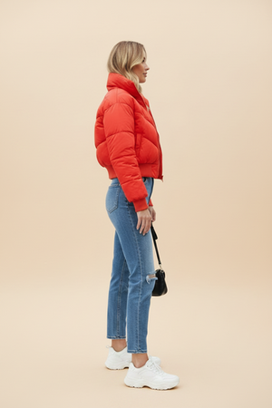Red quilted puffer jacket with hood and front zipper; side view.