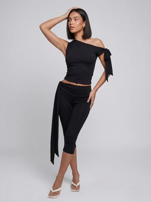 Black two-piece set with an asymmetric tie-shoulder top and cropped tie-waist leggings, front view
