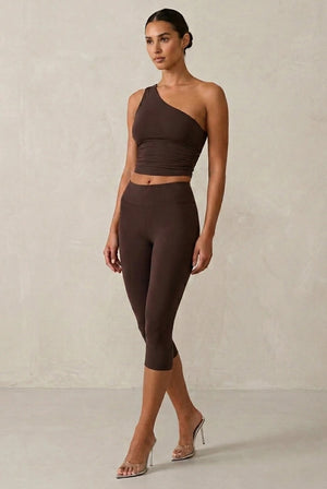 Brown Capri leggings shown with a matching cropped one-shoulder top.