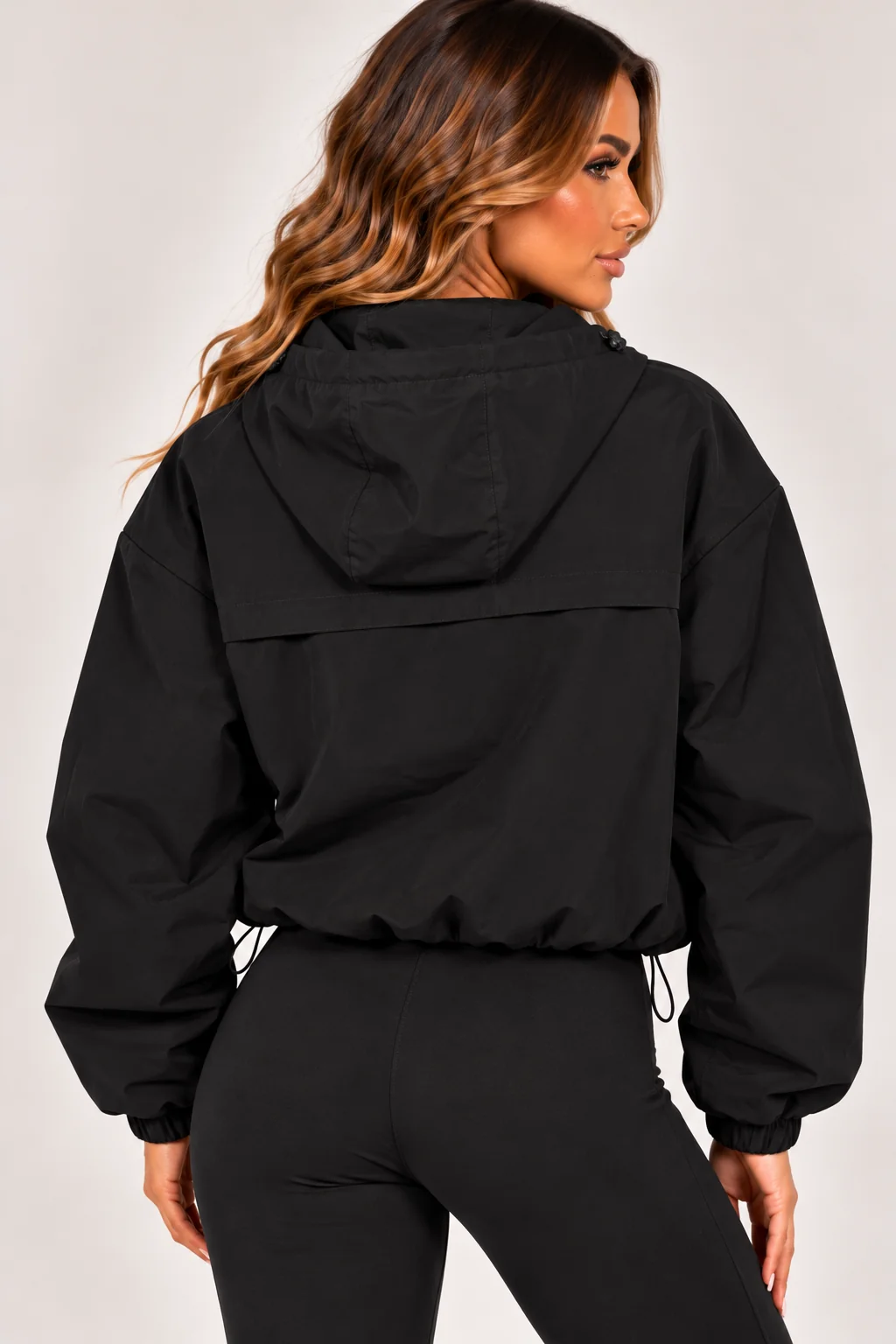Black hooded zip-up windbreaker jacket, rear view with elastic cuffs and pocket zips