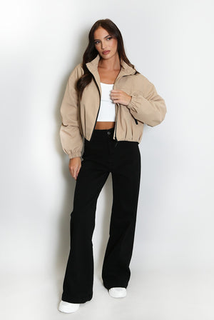 Beige cropped hooded jacket with black zipper and side stripe accents, ribbed hem.