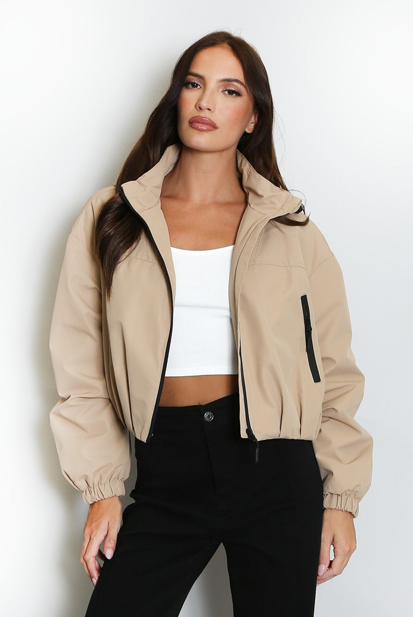 Beige cropped hooded jacket with black zipper, contrast hood lining, elastic cuffs.
