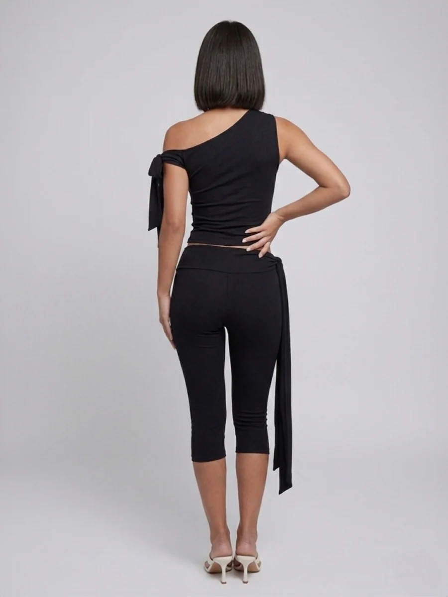 Black two-piece set, back view showing the asymmetric top and cropped tie-waist leggings